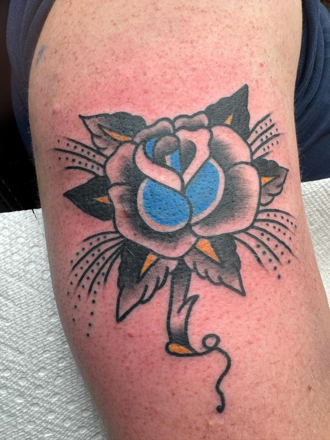 A traditional rose in blue and gray with dot shading, on an upper arm.